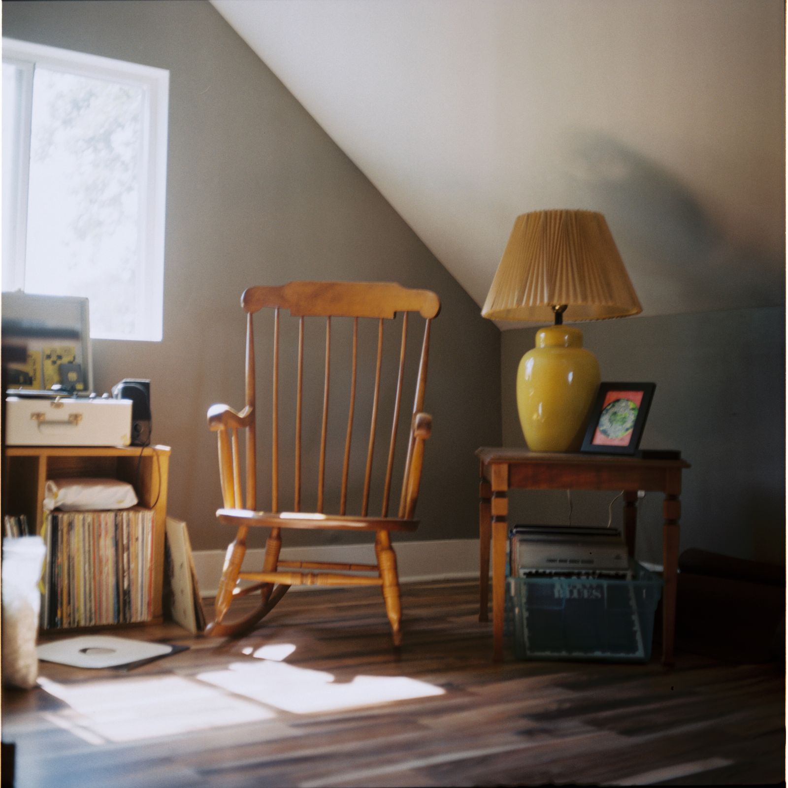 An empty wooden rocking chair beside a lamp and window