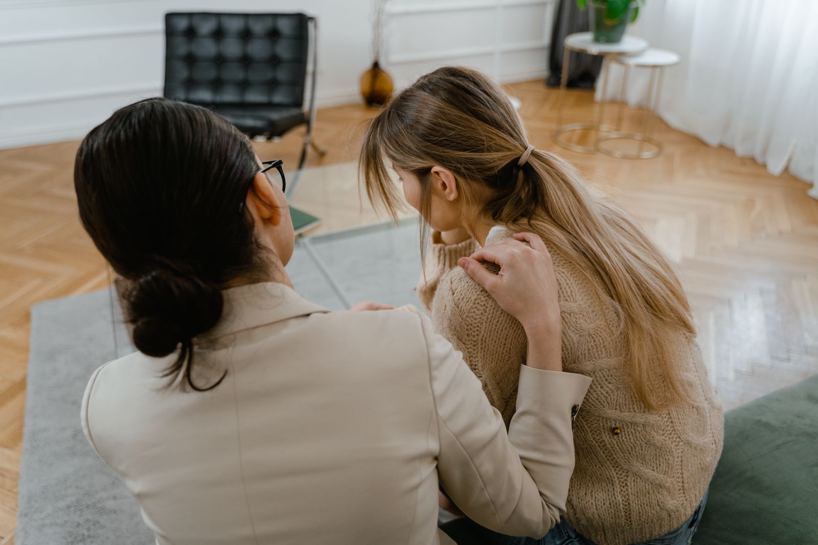A woman resting a reassuring hand on another woman’s shoulder